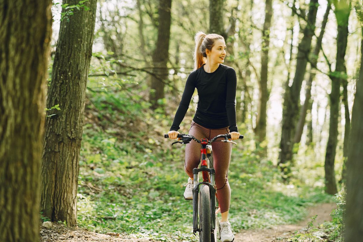 mulher loira de bicicleta no bosque